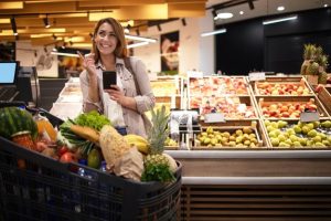 femme-telephone-intelligent-dans-supermarche-debout-pres-etageres-pleines-fruits-epicerie